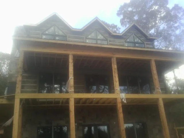 Dormers and porch framing on a large log home under construction — Roof Coating work by our crew in Evergreen